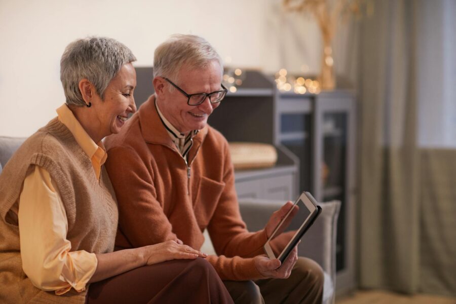 couple smiling while looking at a tablet computer